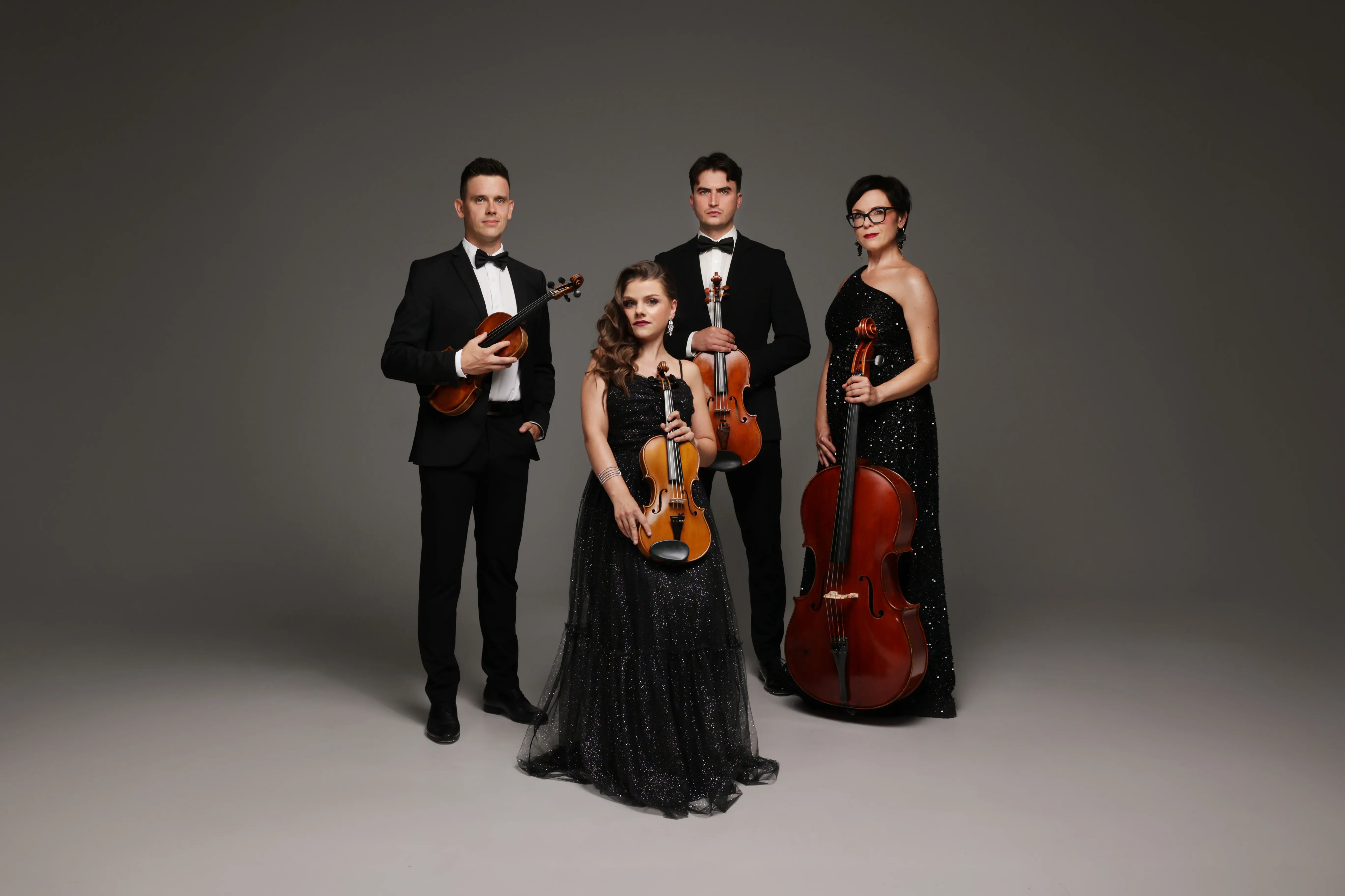 Aura String Quartet: czworo muzyków w strojach wieczorowych z instrumentami na szarym tle
